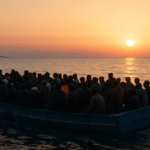 migrant vessel departing the Libyan coast at sunrise